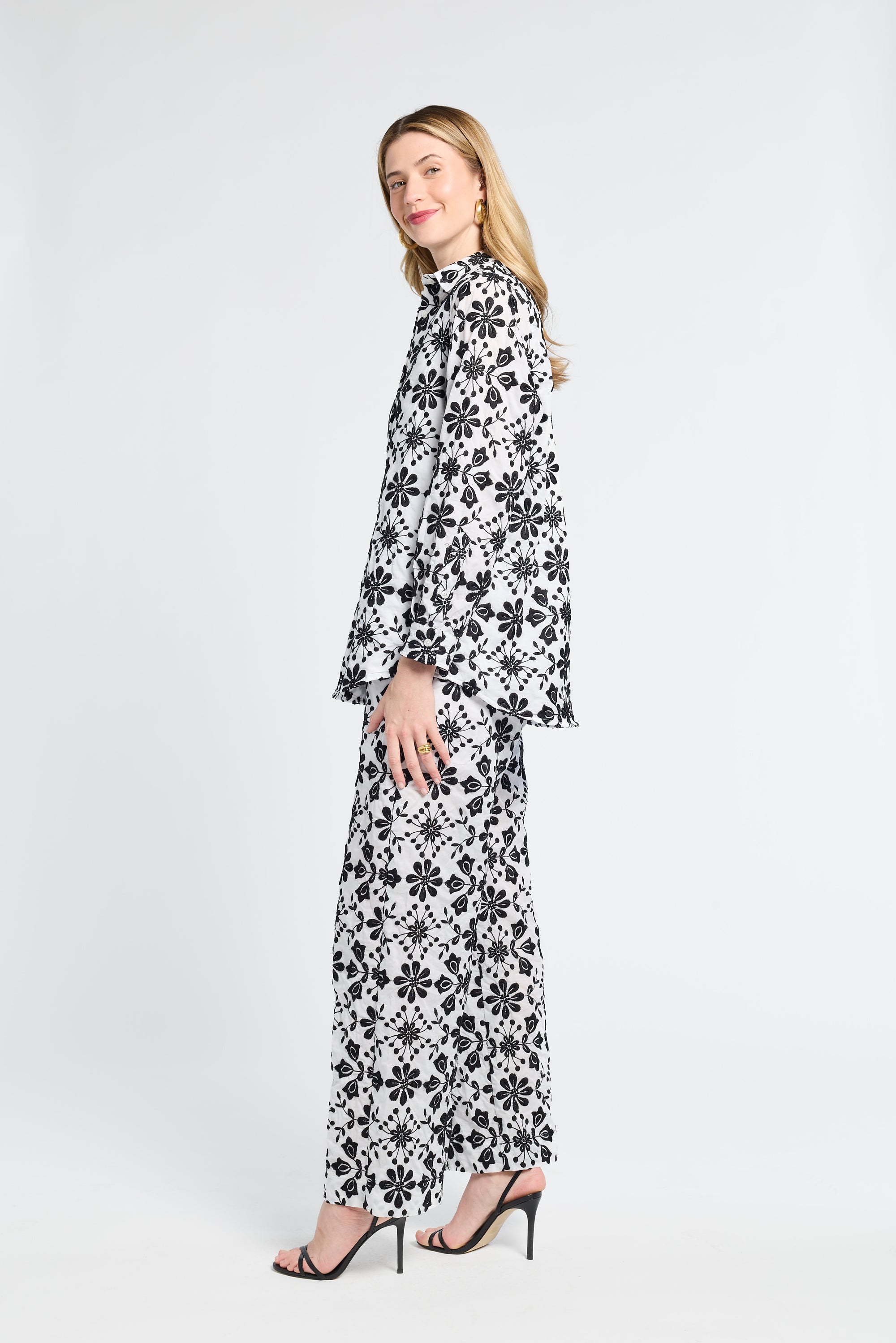 Woman wearing a black and white floral blouse and pants on a white background