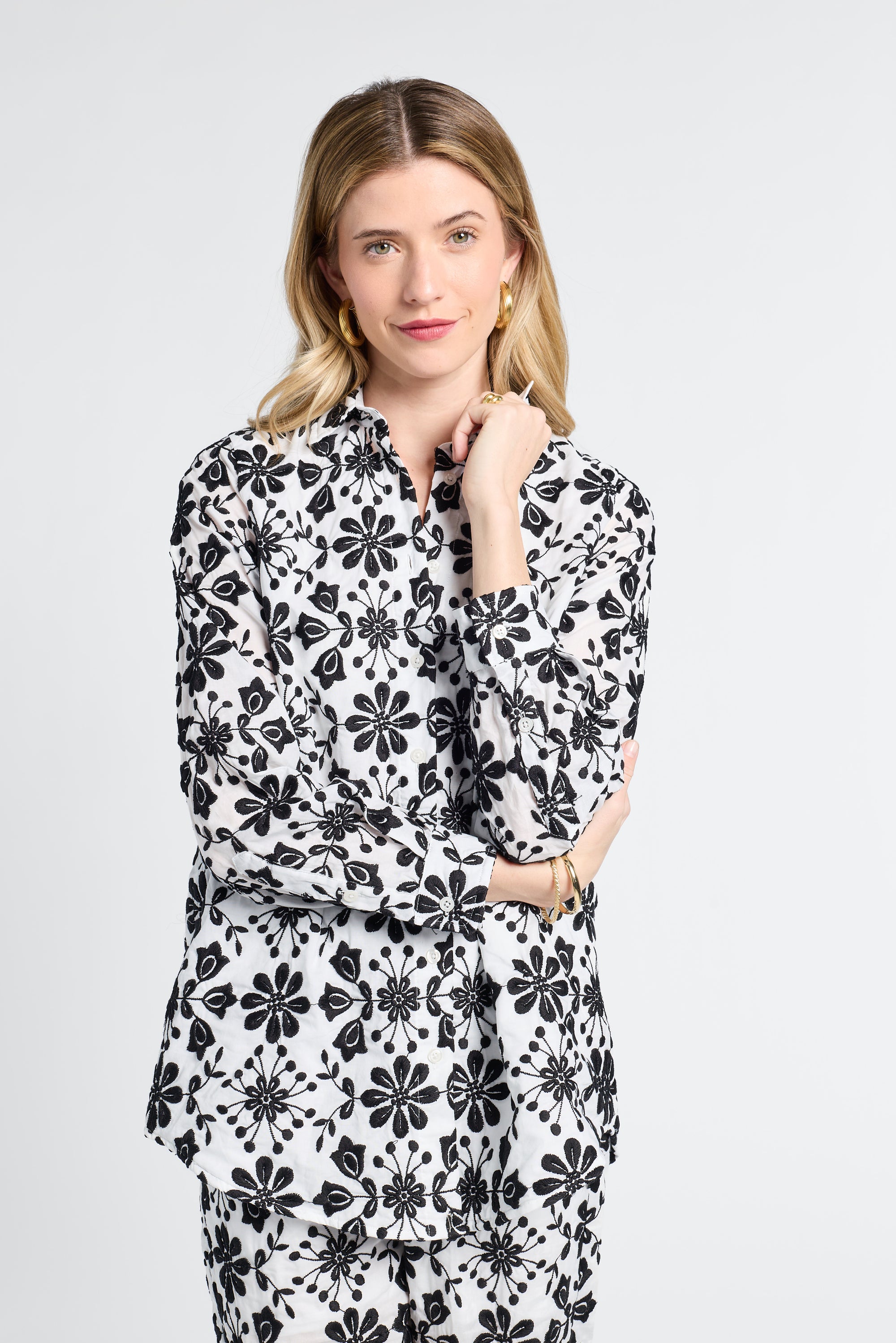Woman wearing a black and white floral long sleeve button down blouse on a light gray background
