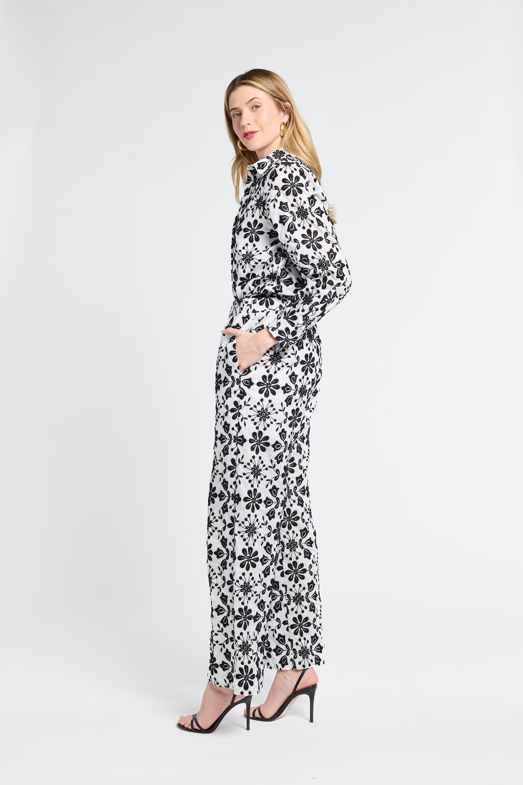 Woman wearing a black and white floral blouse and matching pants on a white background