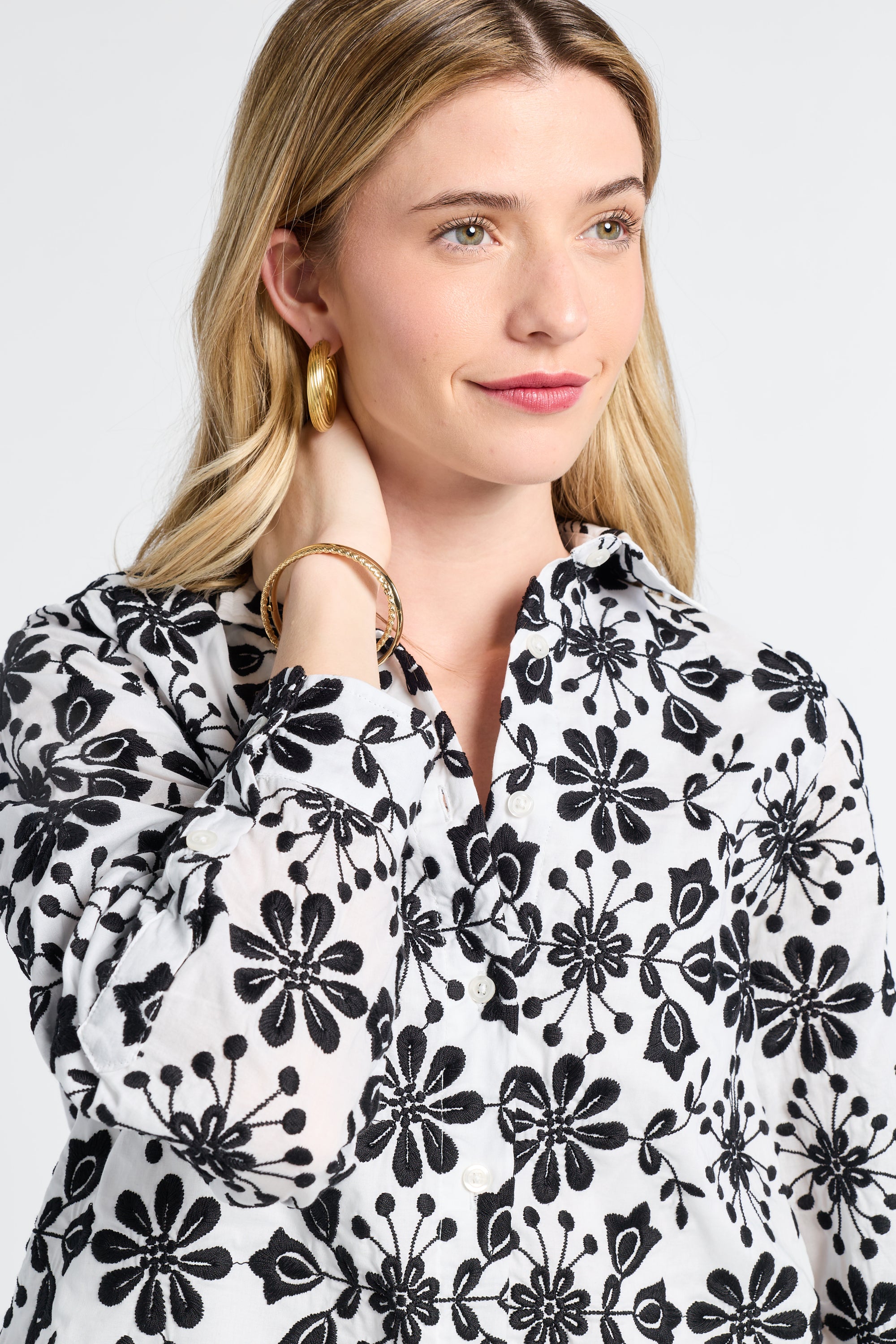 Woman modeling a black and white floral long sleeve blouse against a plain background