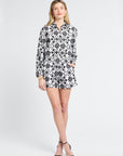 Woman wearing a black and white floral blouse and matching shorts on a white background