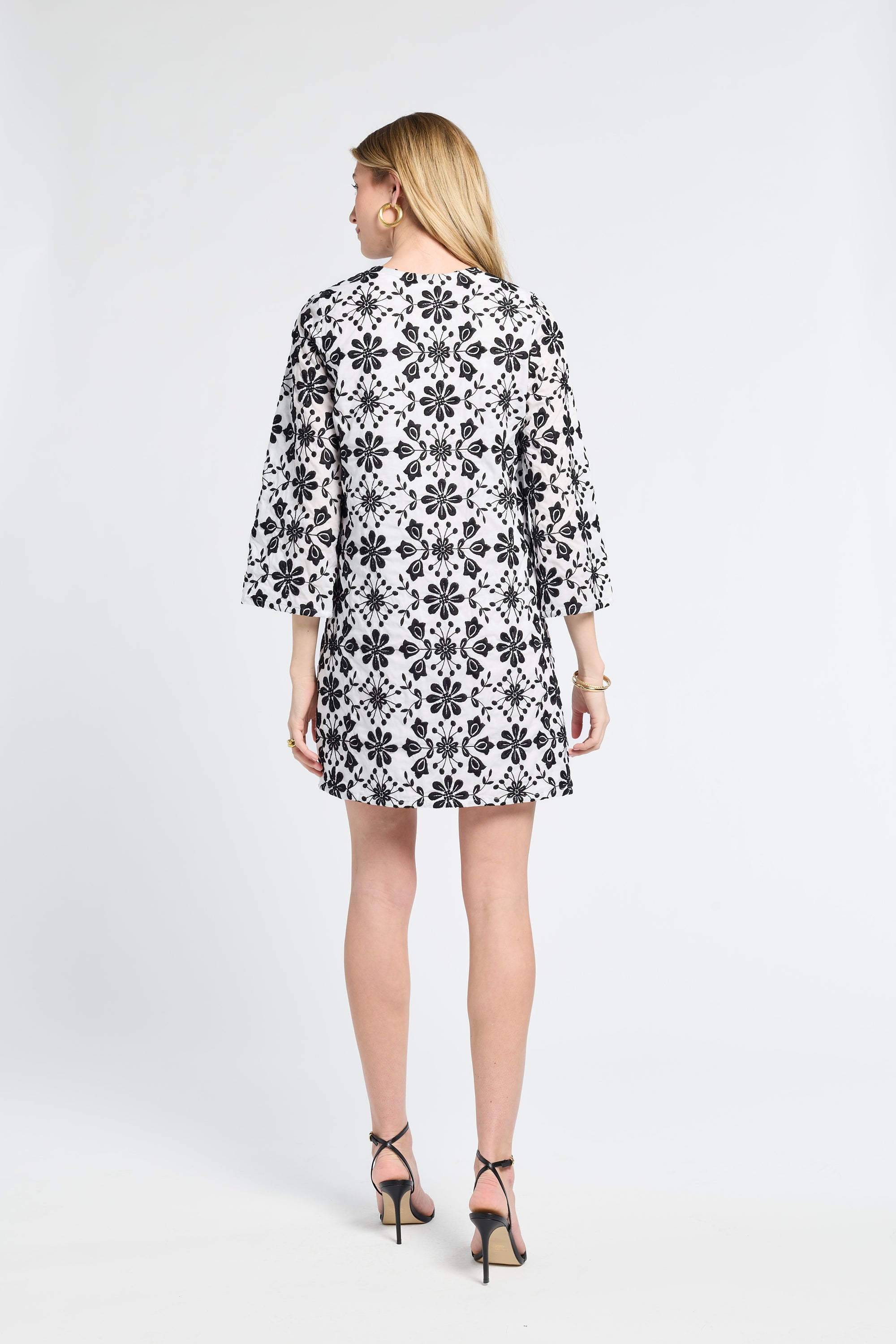 Woman modeling a black and white floral detailed dress on a white background
