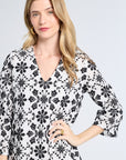 Woman wearing a black and white floral patterned mini dress on a light gray background