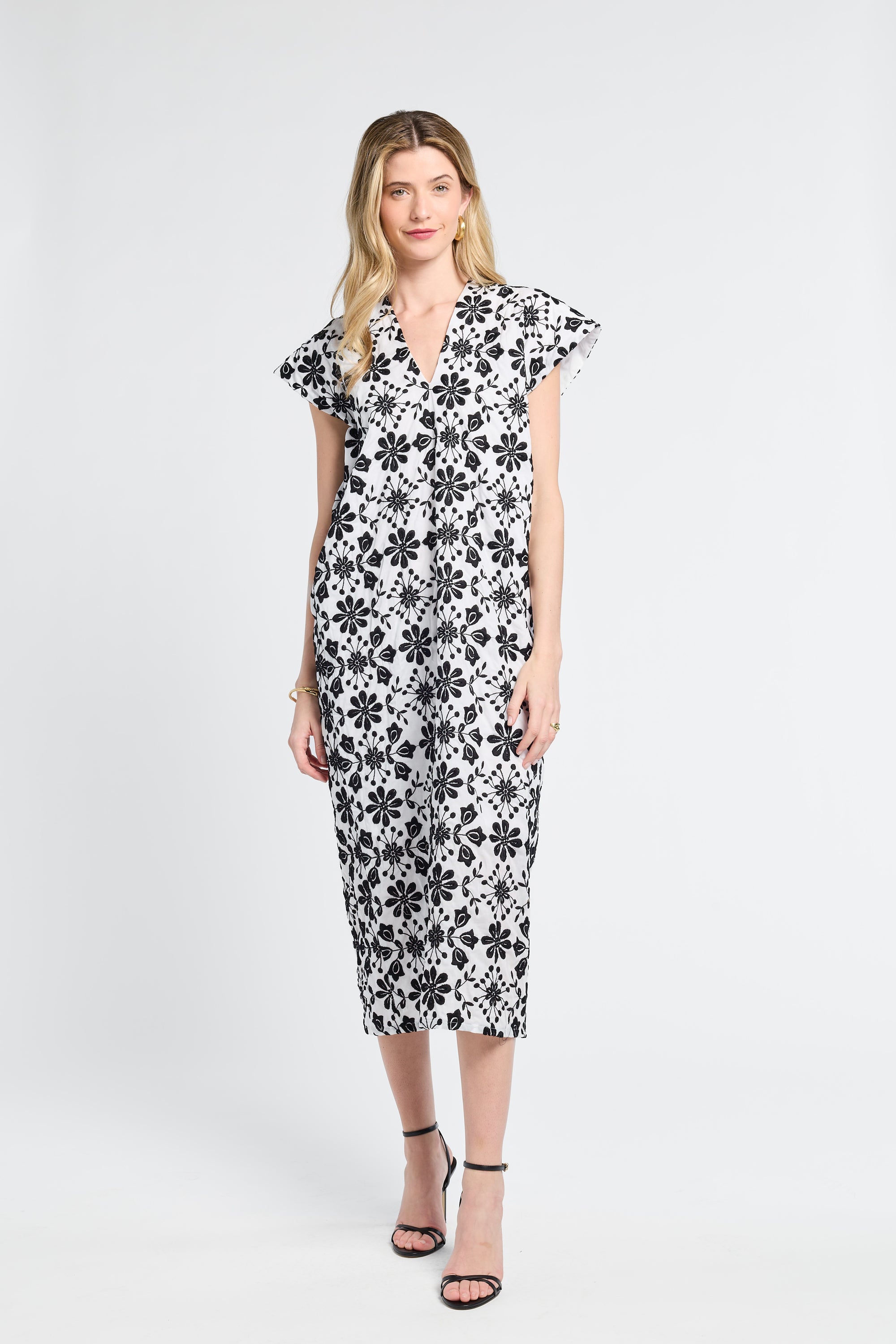 Woman wearing a black and white floral caftan on a white background