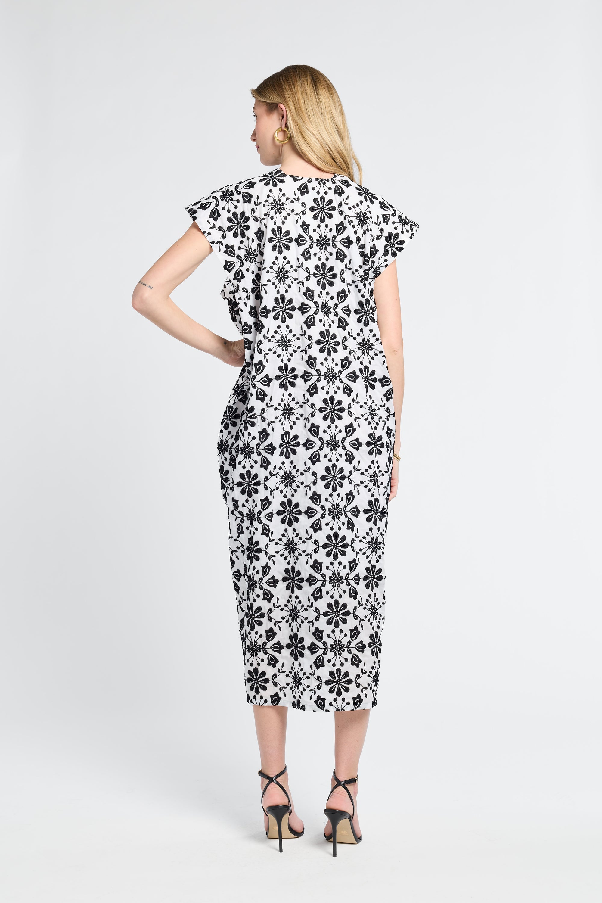 Woman wearing a black and white floral maxi dress on a light gray background