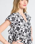 Woman wearing a black floral patterned caftan with gold jewelry on a white background