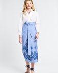 Woman wearing a white blouse and blue embroidered floral skirt on a white background