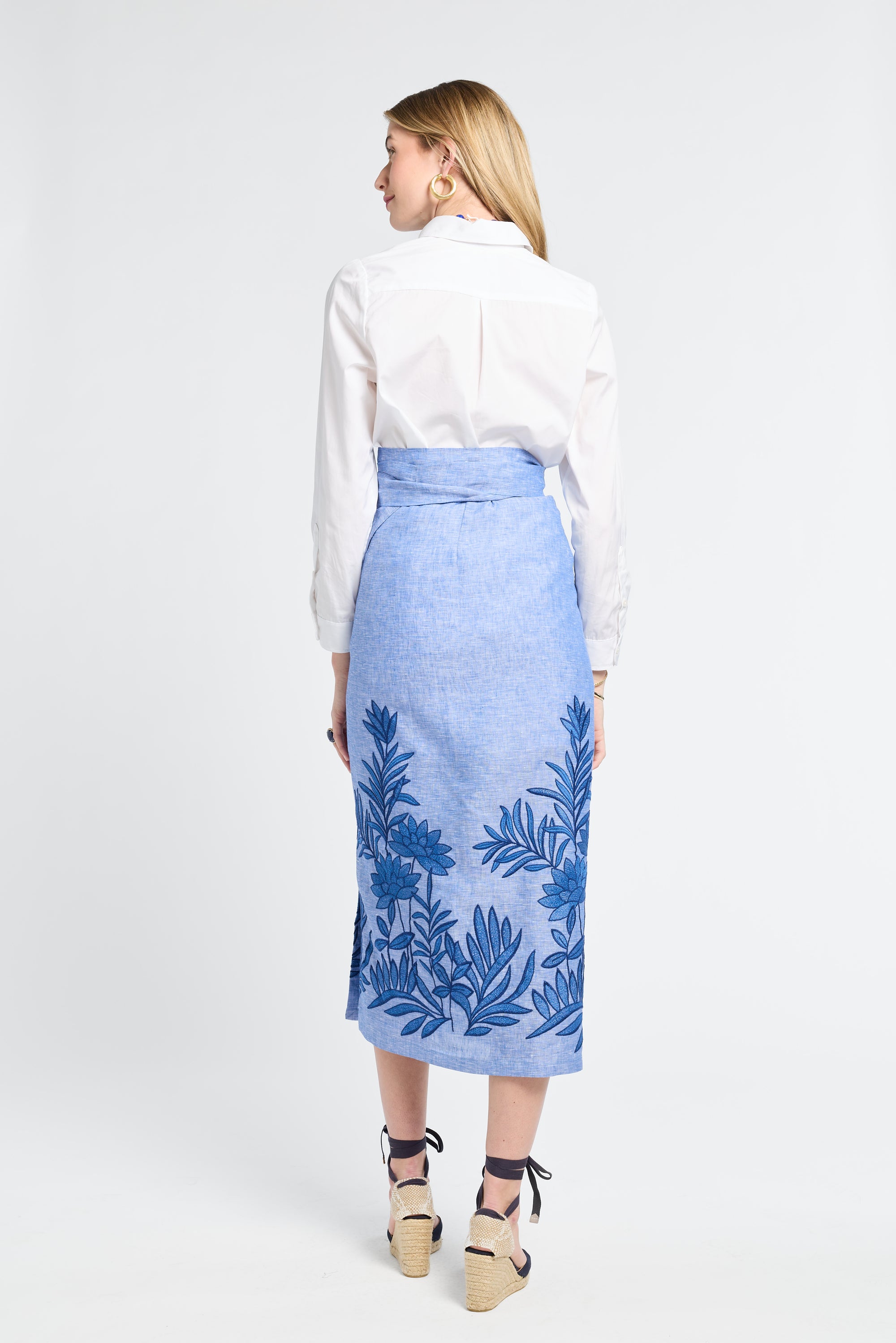 Woman modeling a white shirt and blue floral skirt on a white background