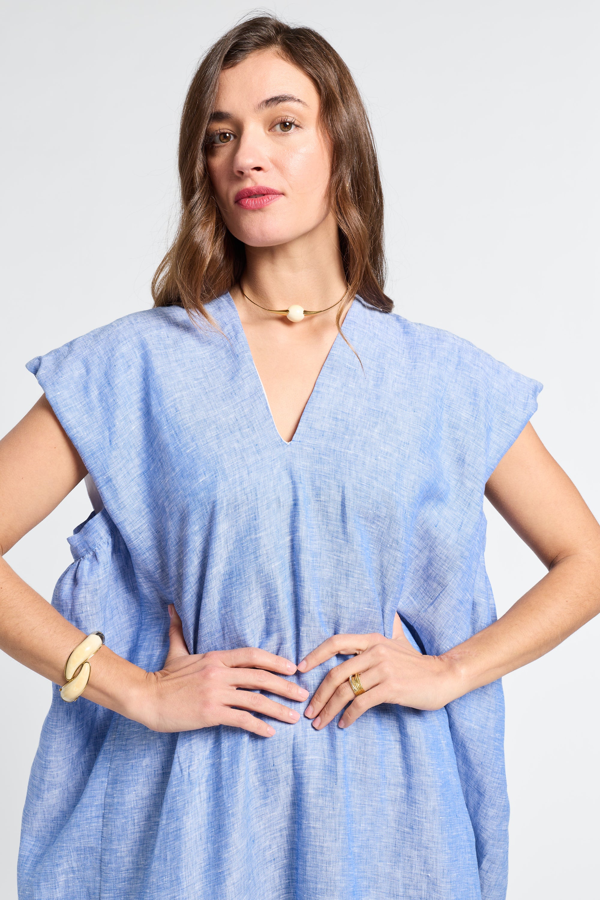 Woman wearing a light blue v-neck caftan against a white background