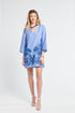 Woman wearing a blue caftan with floral embroidery on a white background