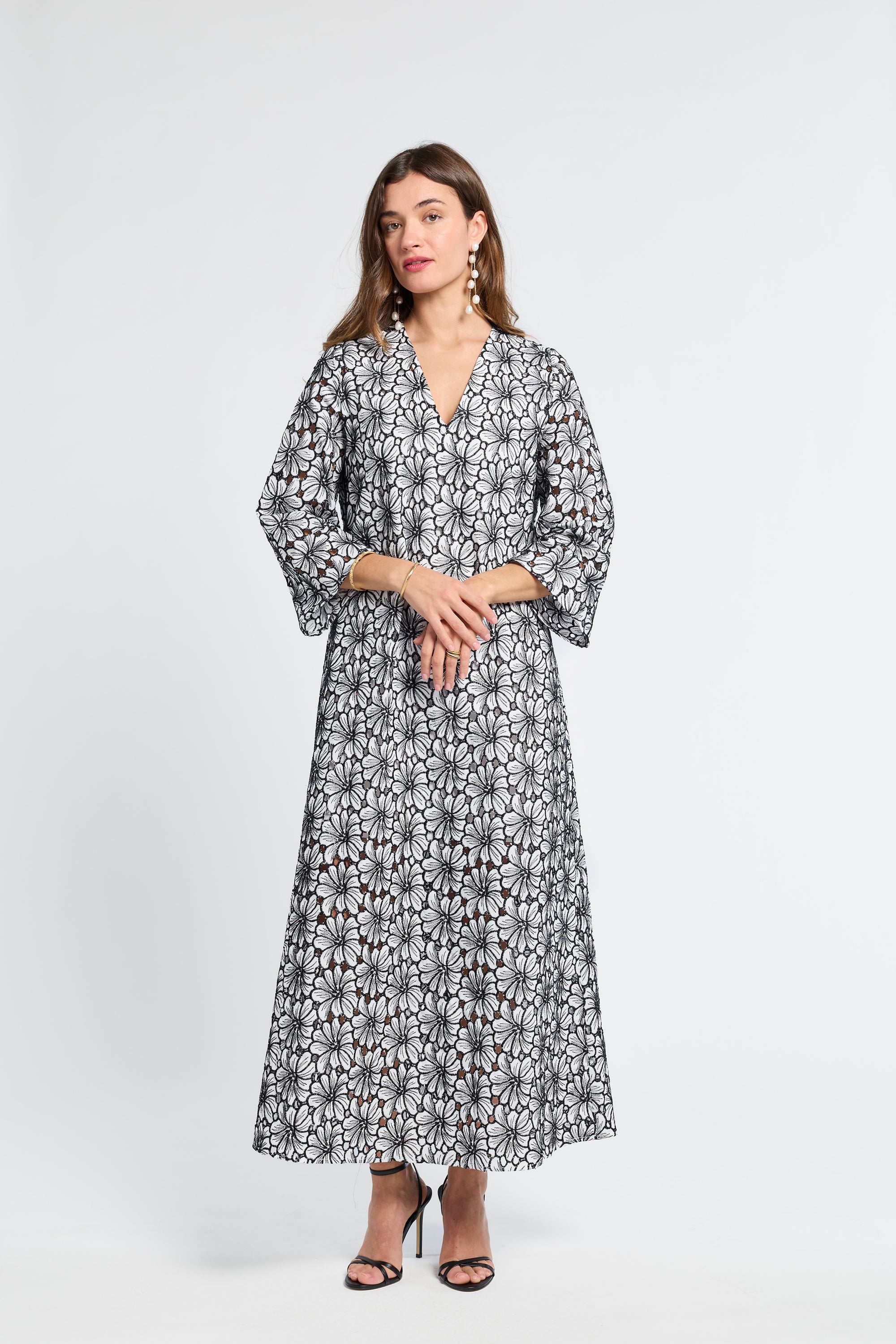Woman wearing a black and white floral v-neck dress on a white background