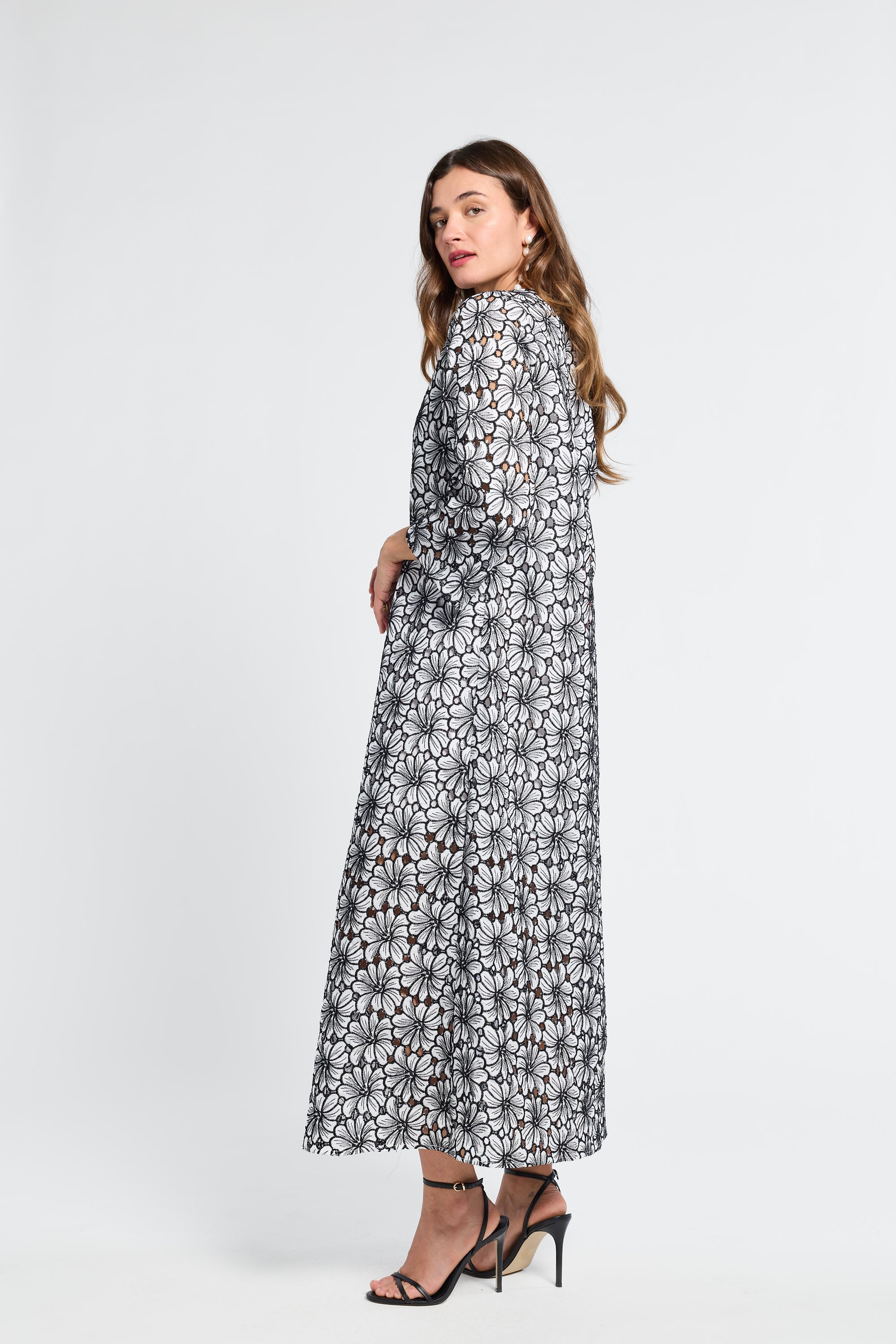 Woman wearing a black and white floral embroidered dress on a white background
