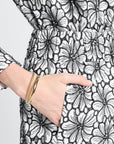 Close-up of a hand wearing a gold bracelet on black and white floral shorts.