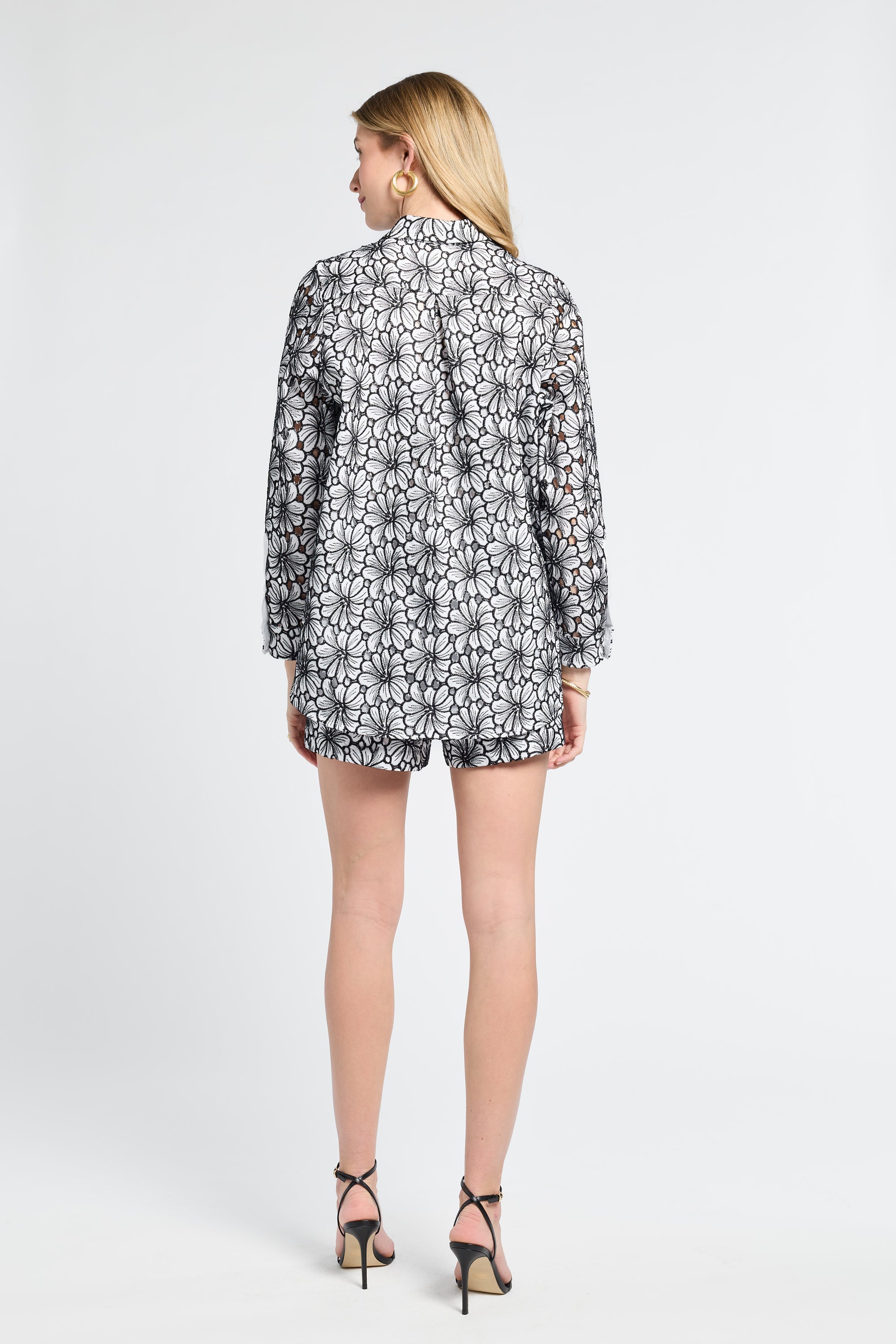 Woman wearing a floral patterned blouse and matching shorts on a white background
