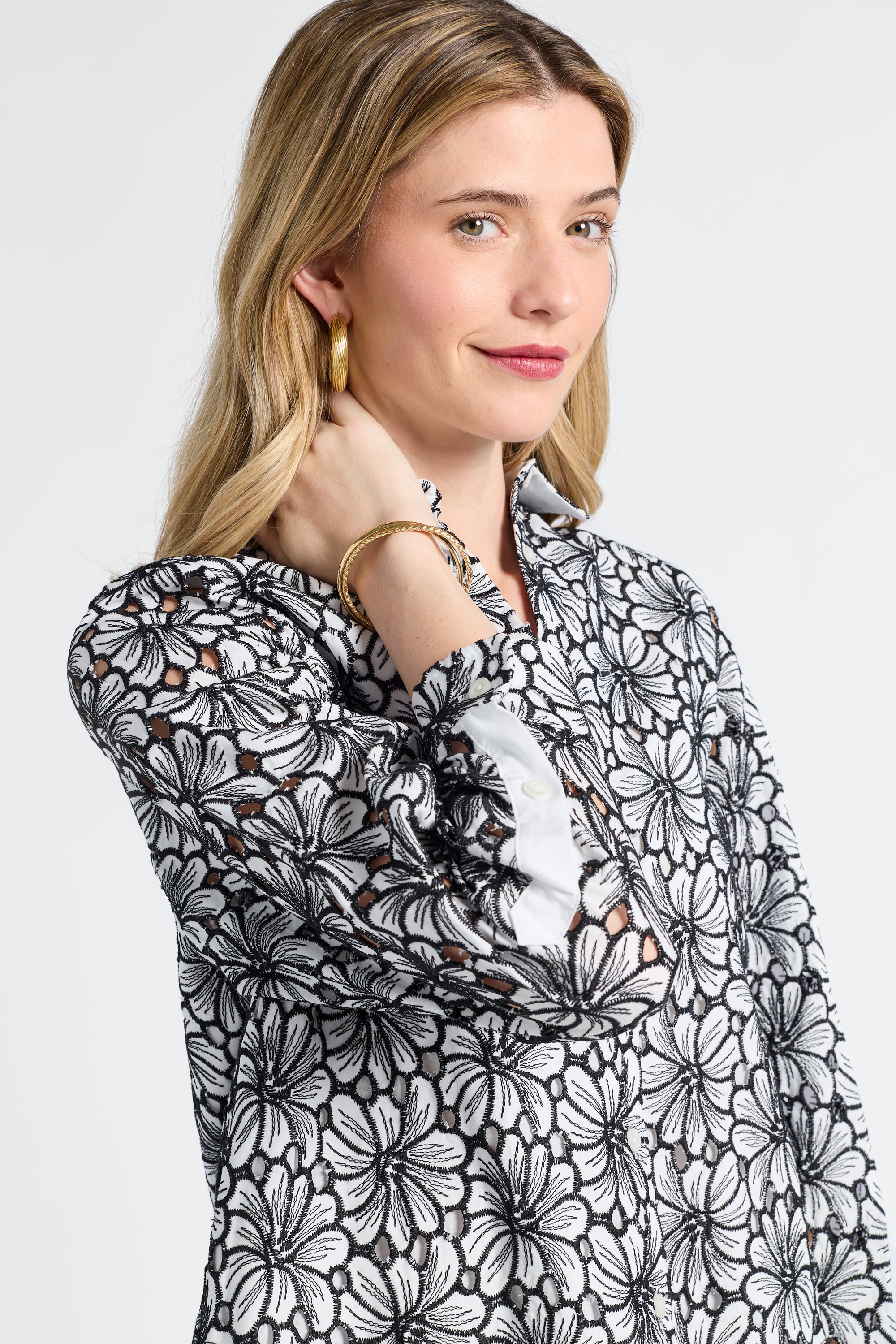 Woman modeling a black floral patterned blouse on a white background