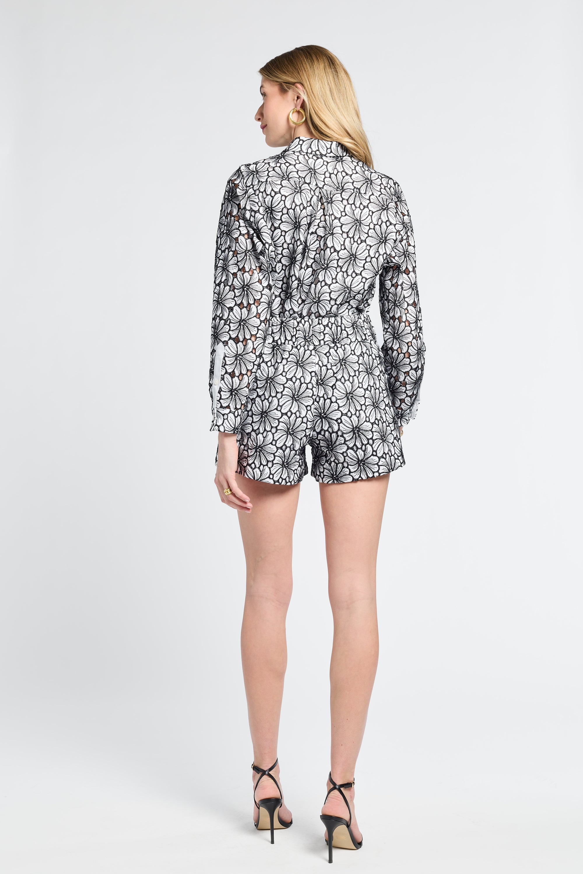 Woman wearing black and white patterned shorts and heels on a white background