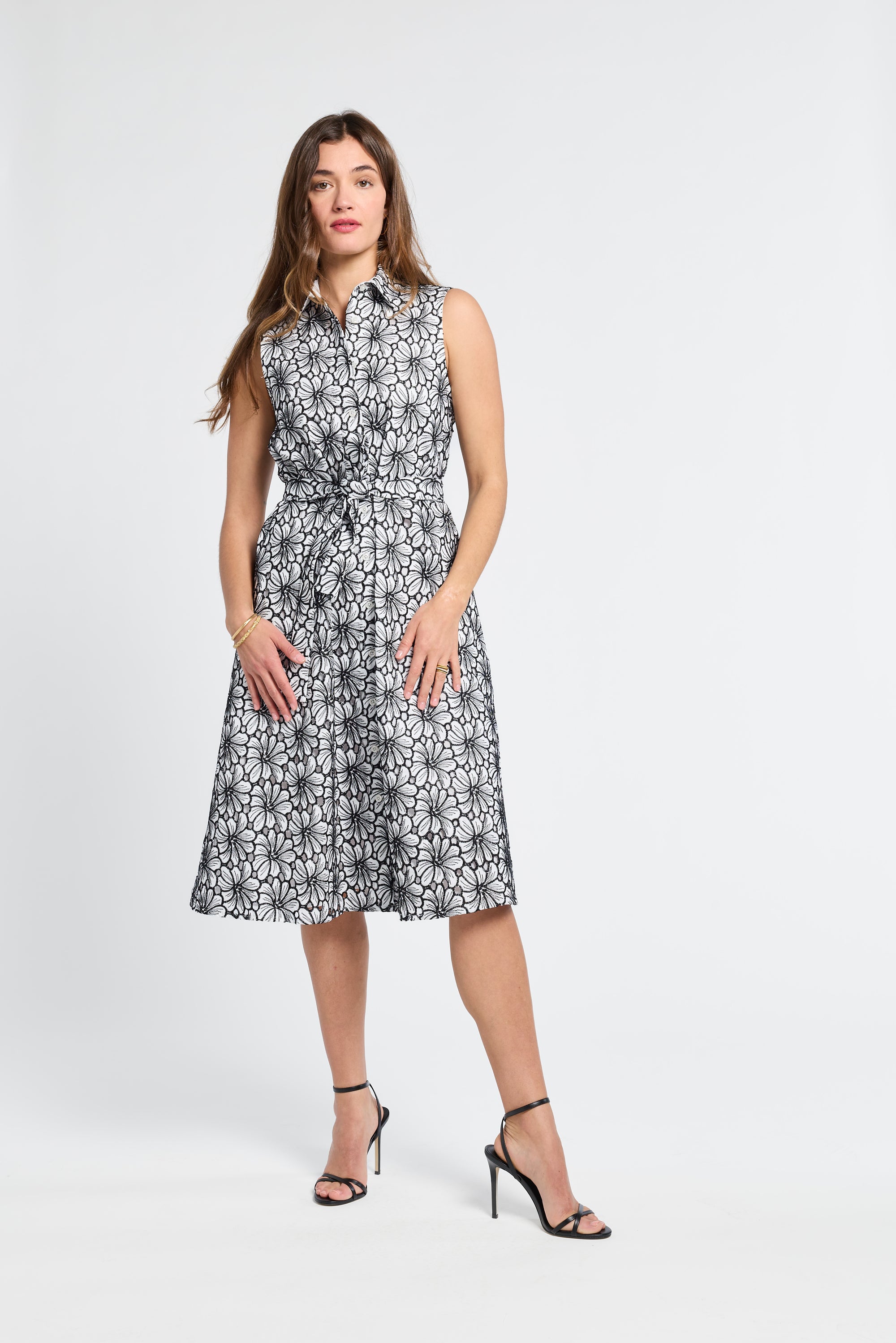 Woman wearing a sleeveless black and white floral dress on a white background