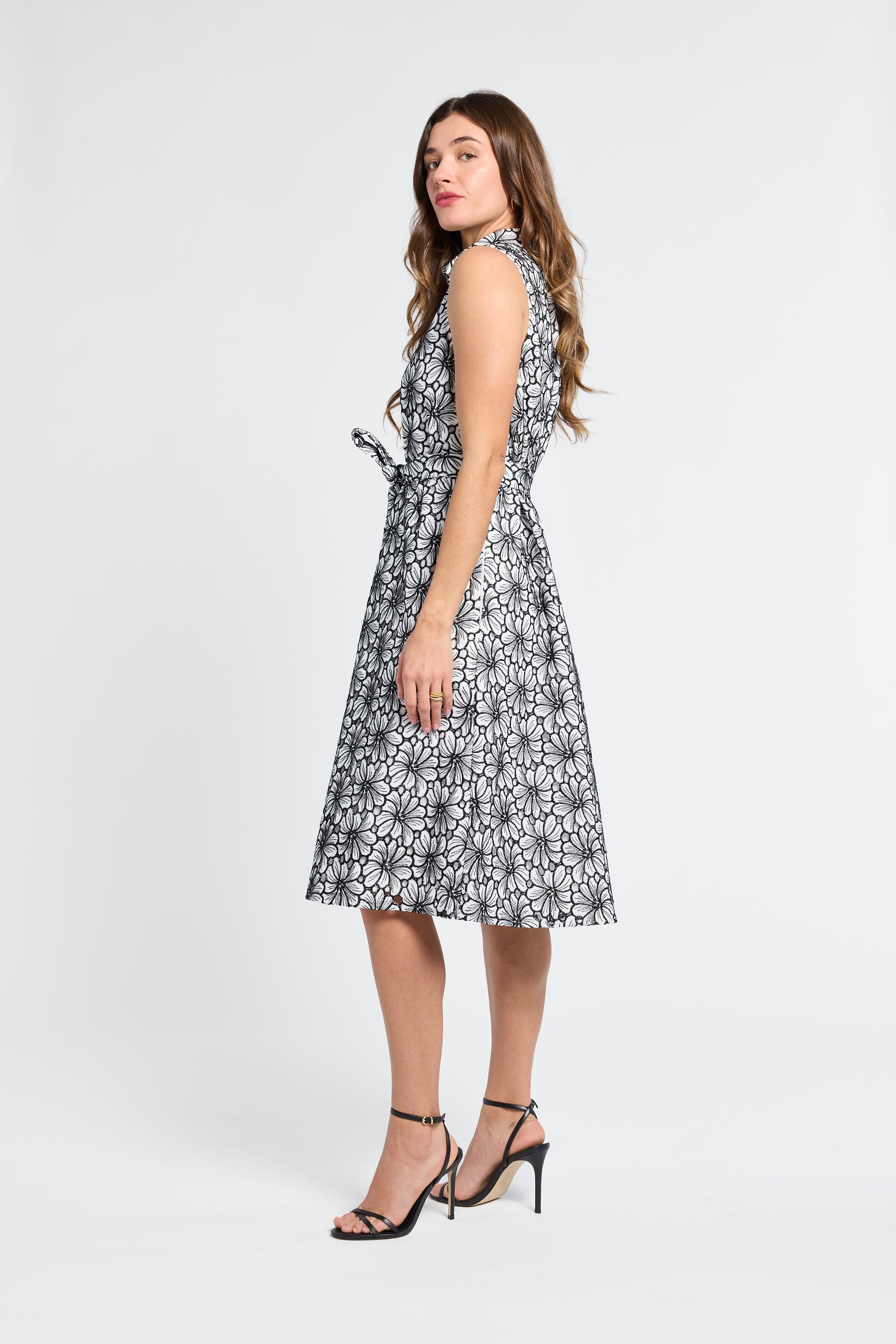 Woman wearing a black and white floral  mid-length dress on a white background