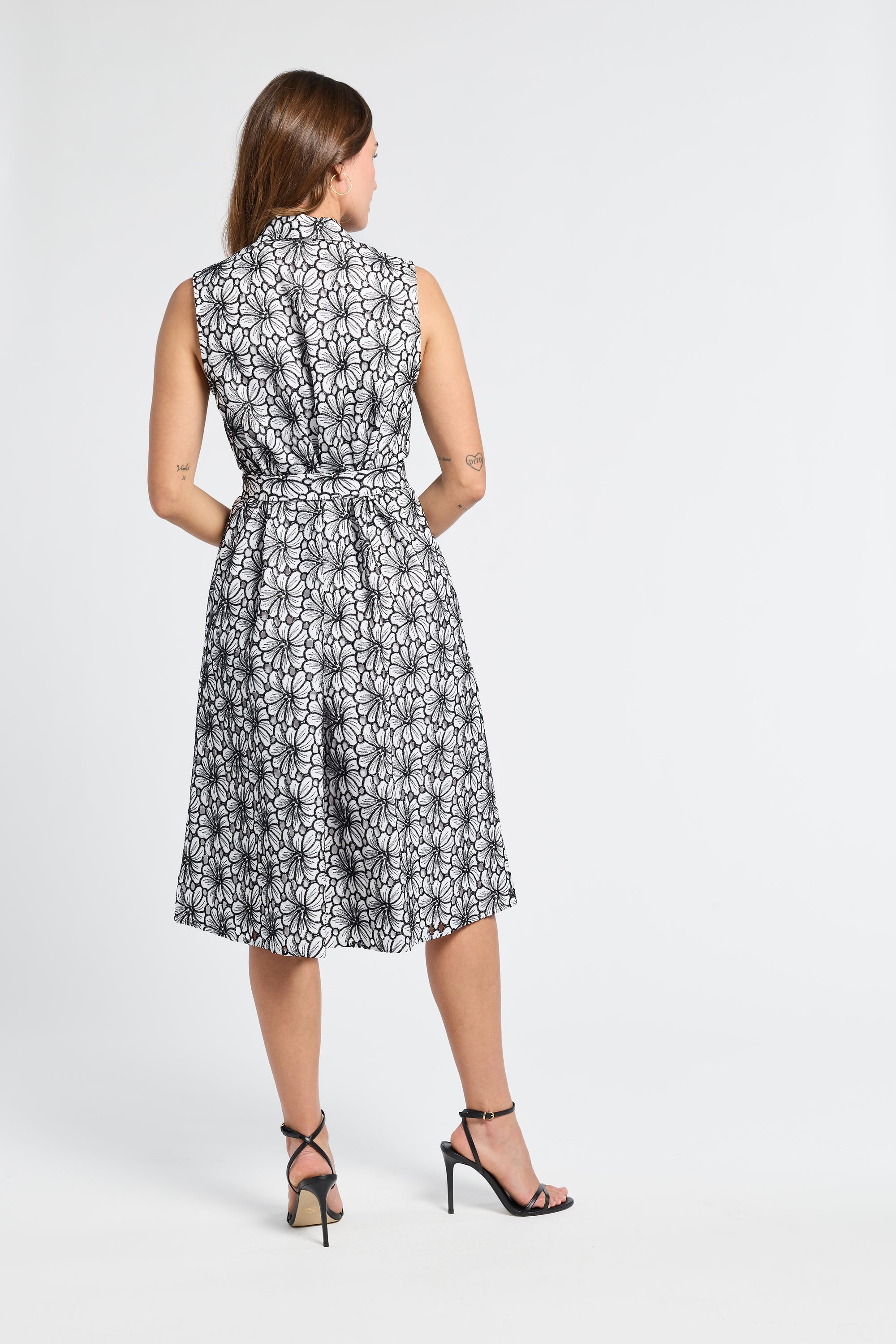 Woman wearing a sleeveless mid-length floral dress on a white background