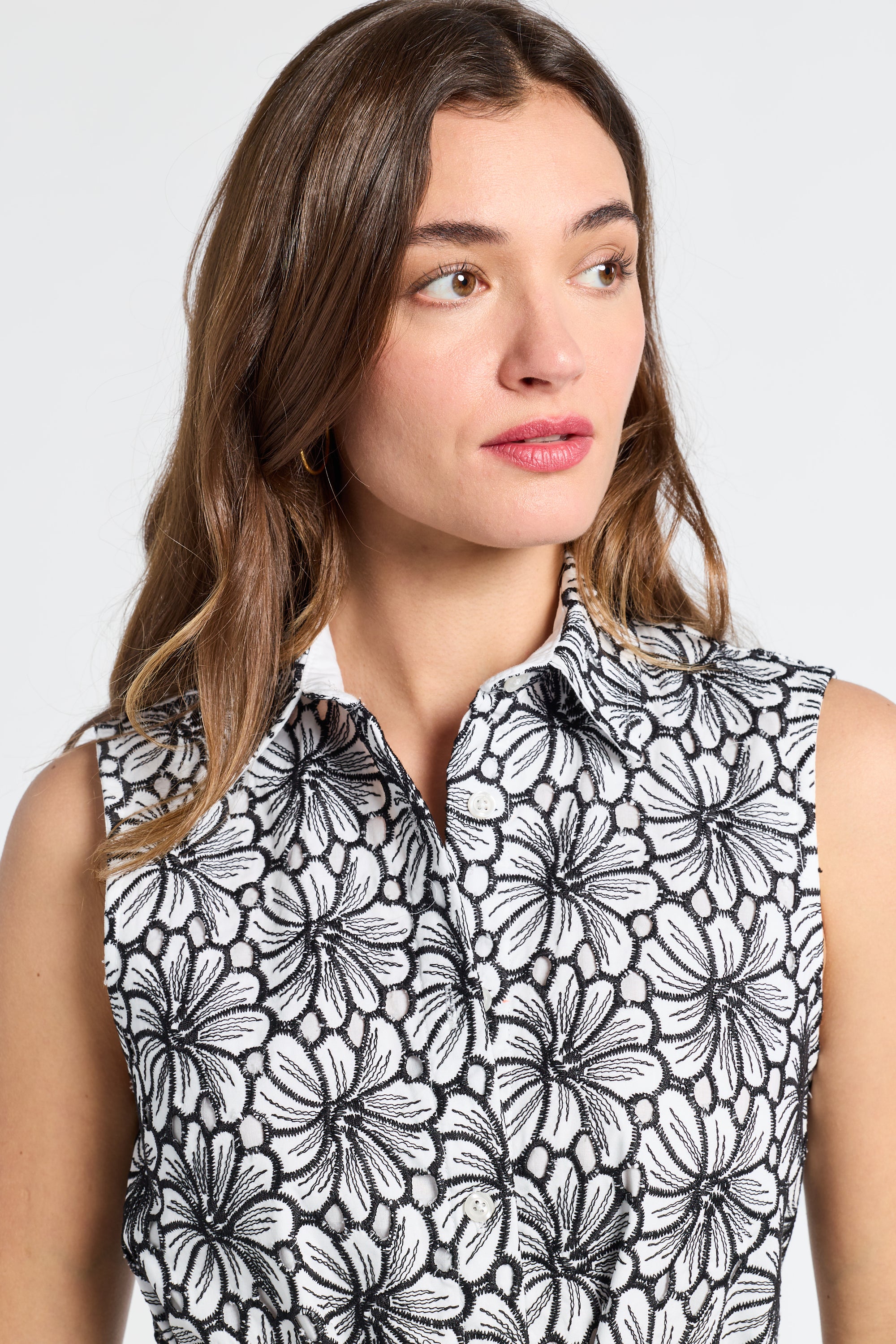 Woman wearing a sleeveless dress with black floral pattern on a white background