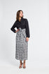 Woman wearing a black and white embroidered patterned skirt on a white background