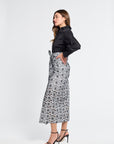 Woman wearing a black blouse and floral black and white embroidered skirt on a white background