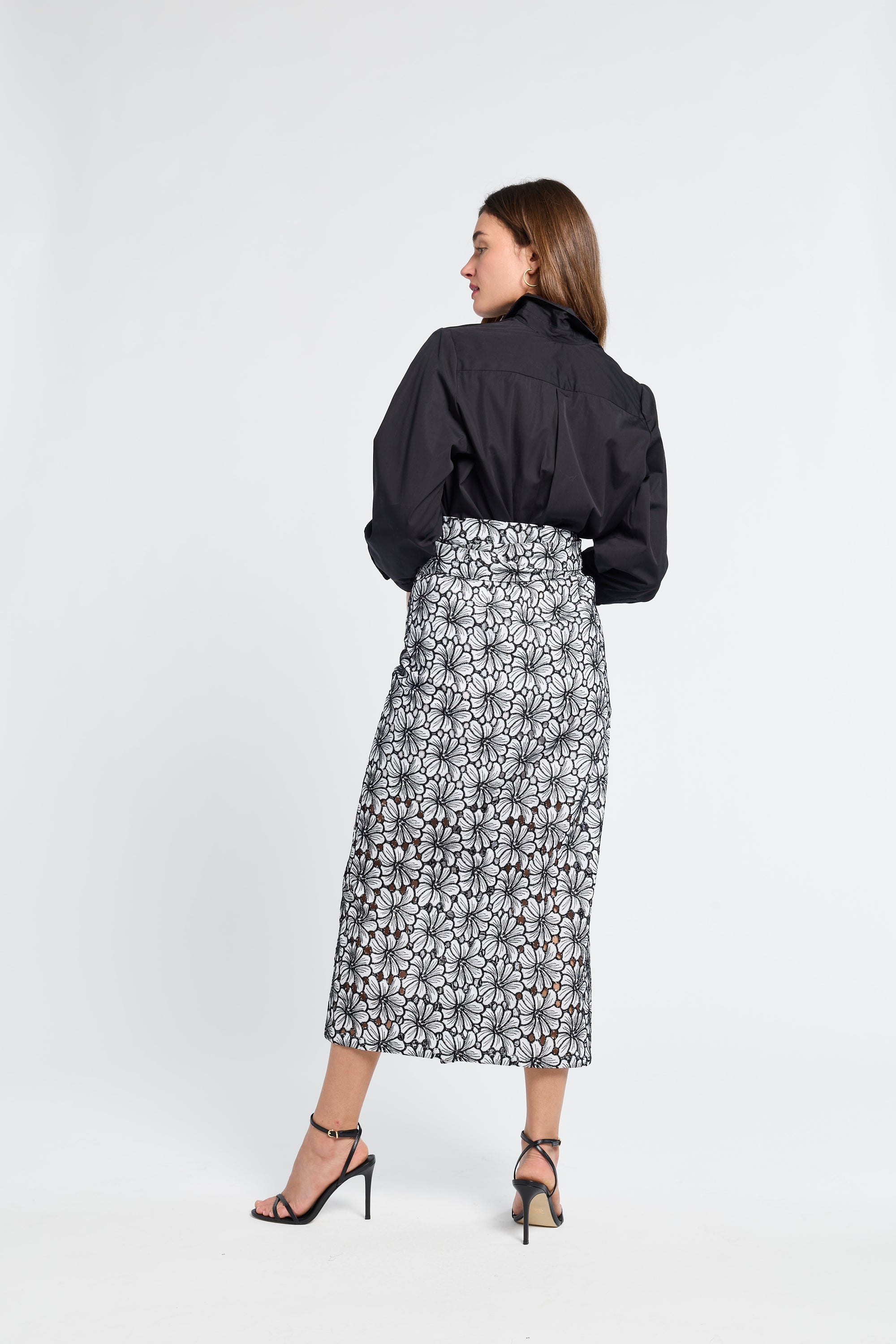 Woman modeling a black blouse and floral skirt on a white background