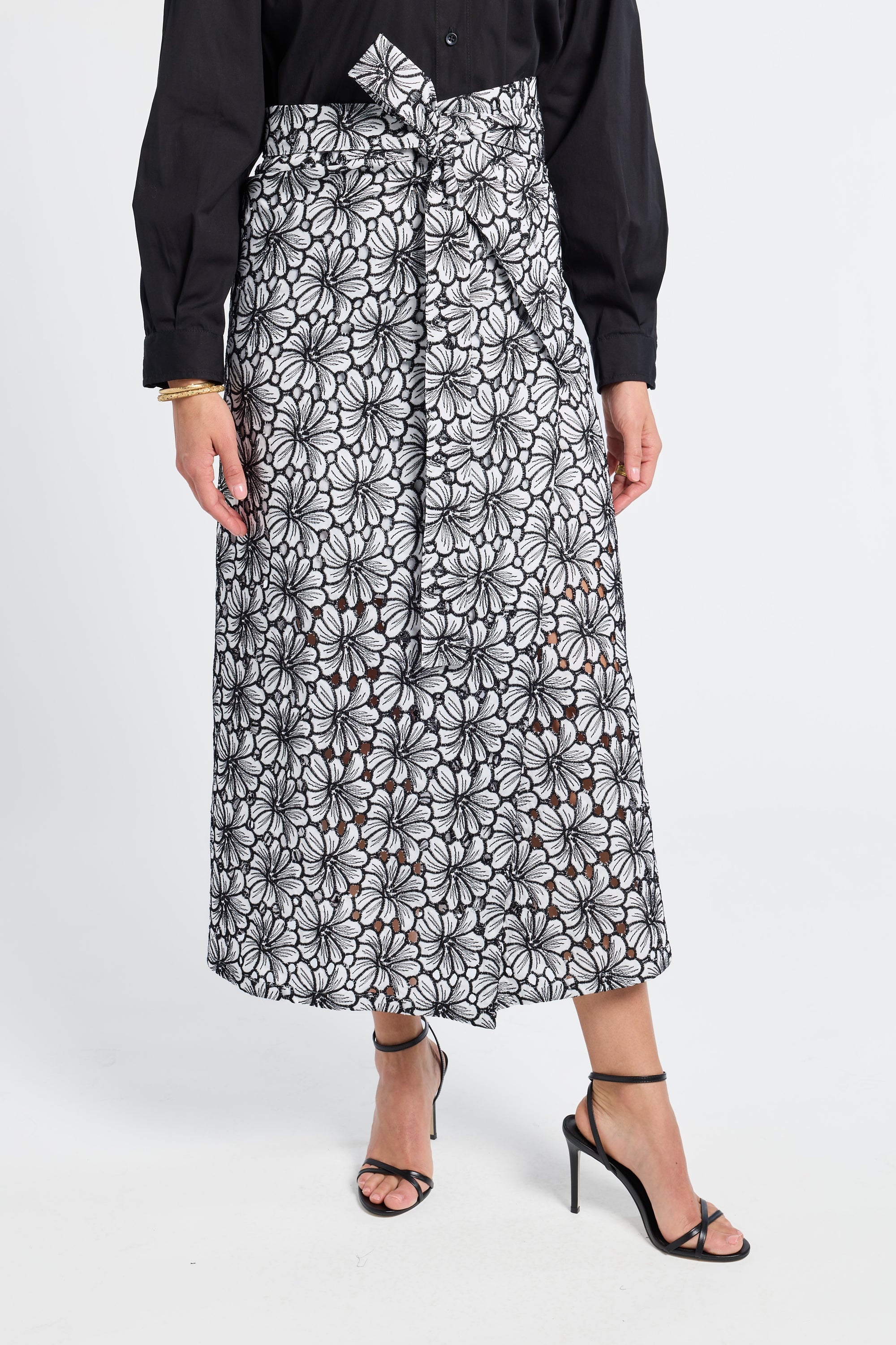 Person wearing a black and white floral patterned skirt on a white background