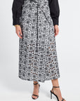 Person wearing a black and white floral patterned skirt on a white background