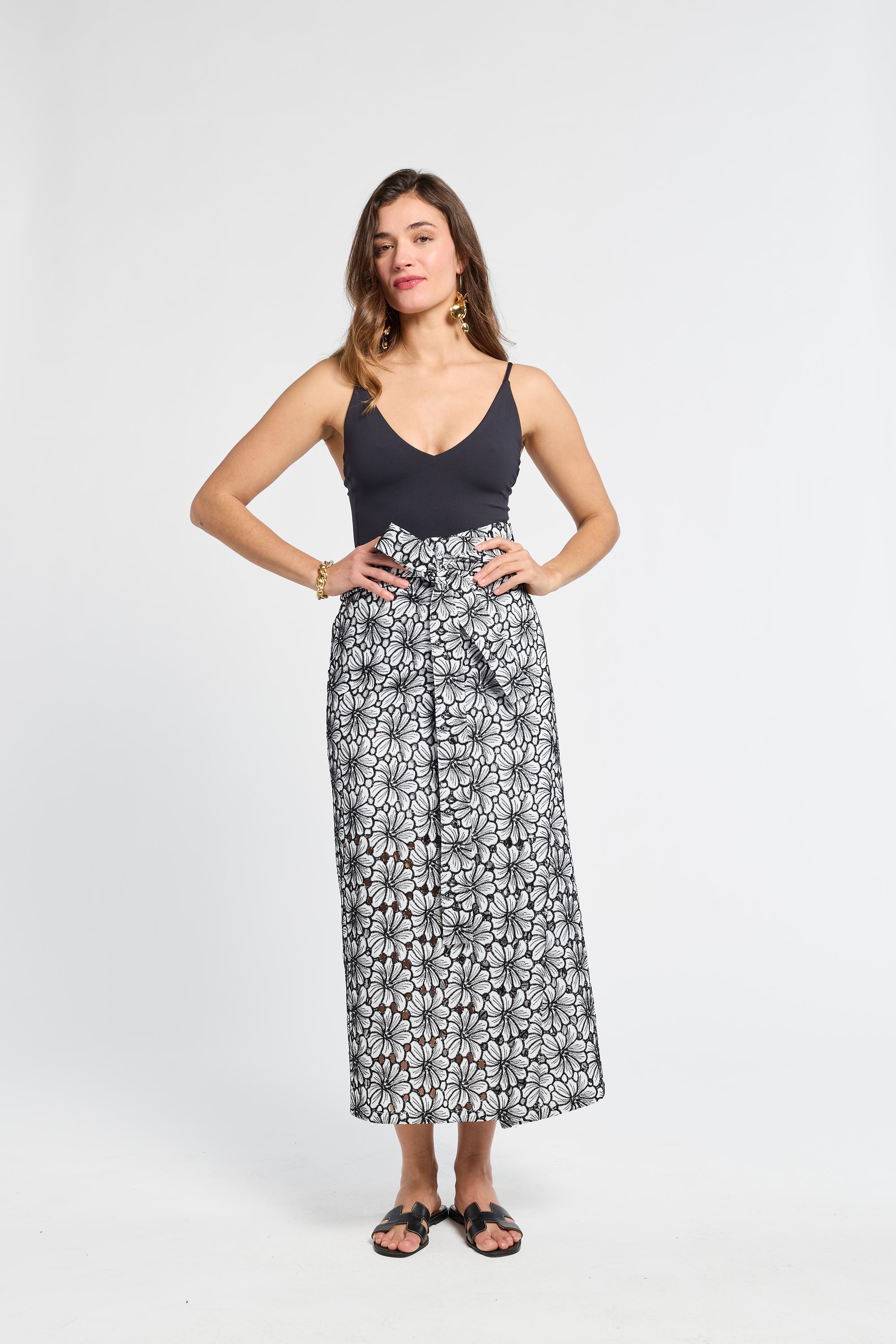 Woman wearing a black top and floral embroidered skirt on a white background