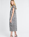Woman wearing a black and white floral maxi dress against a white backdrop