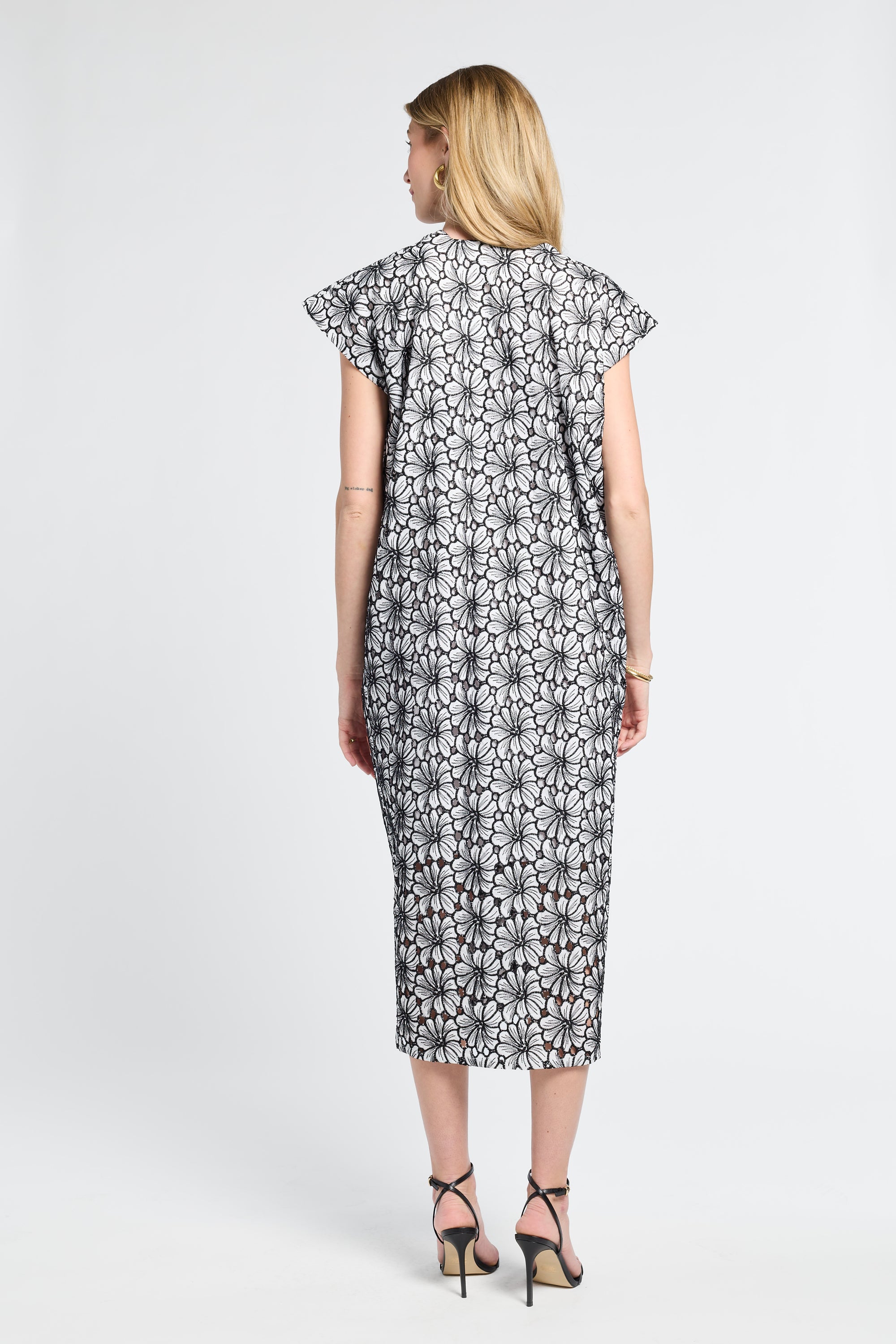 Woman modeling a black and white floral dress on a white background