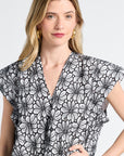 Woman wearing a black and white floral patterned v-neck caftan against a white backdrop
