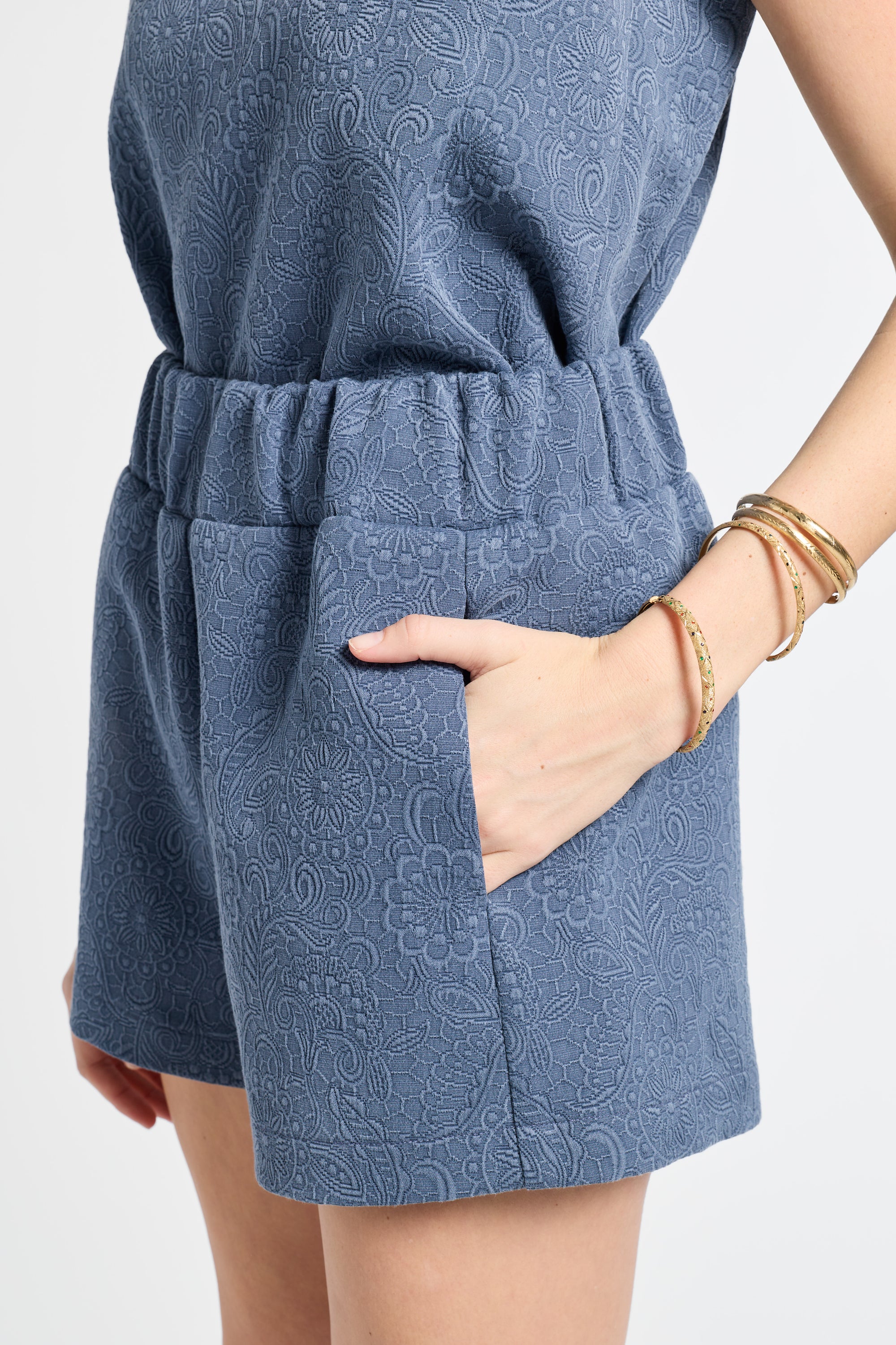 Blue patterned shorts modeled by a person on a light gray background
