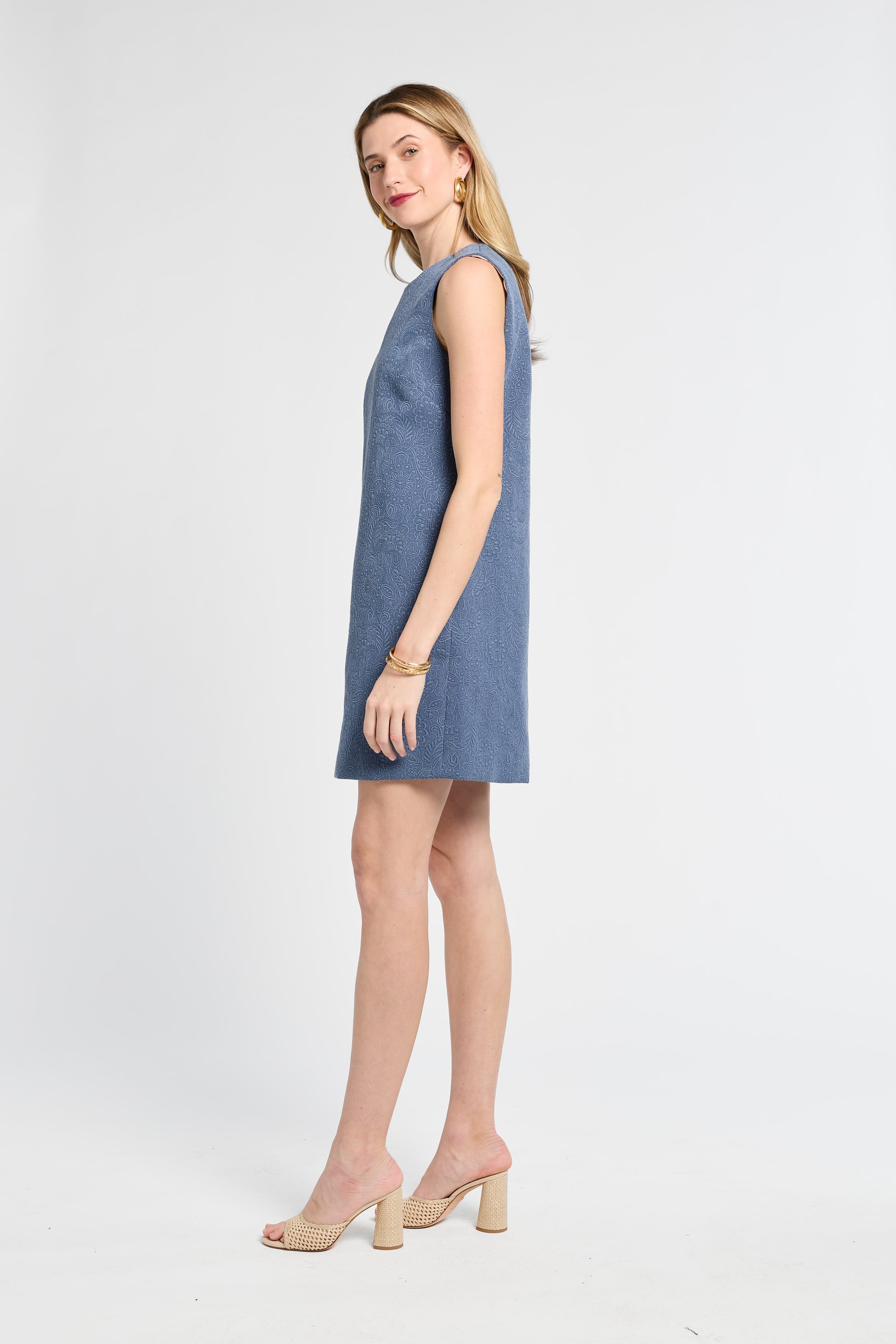 Woman modeling a floral blue dress on a white background