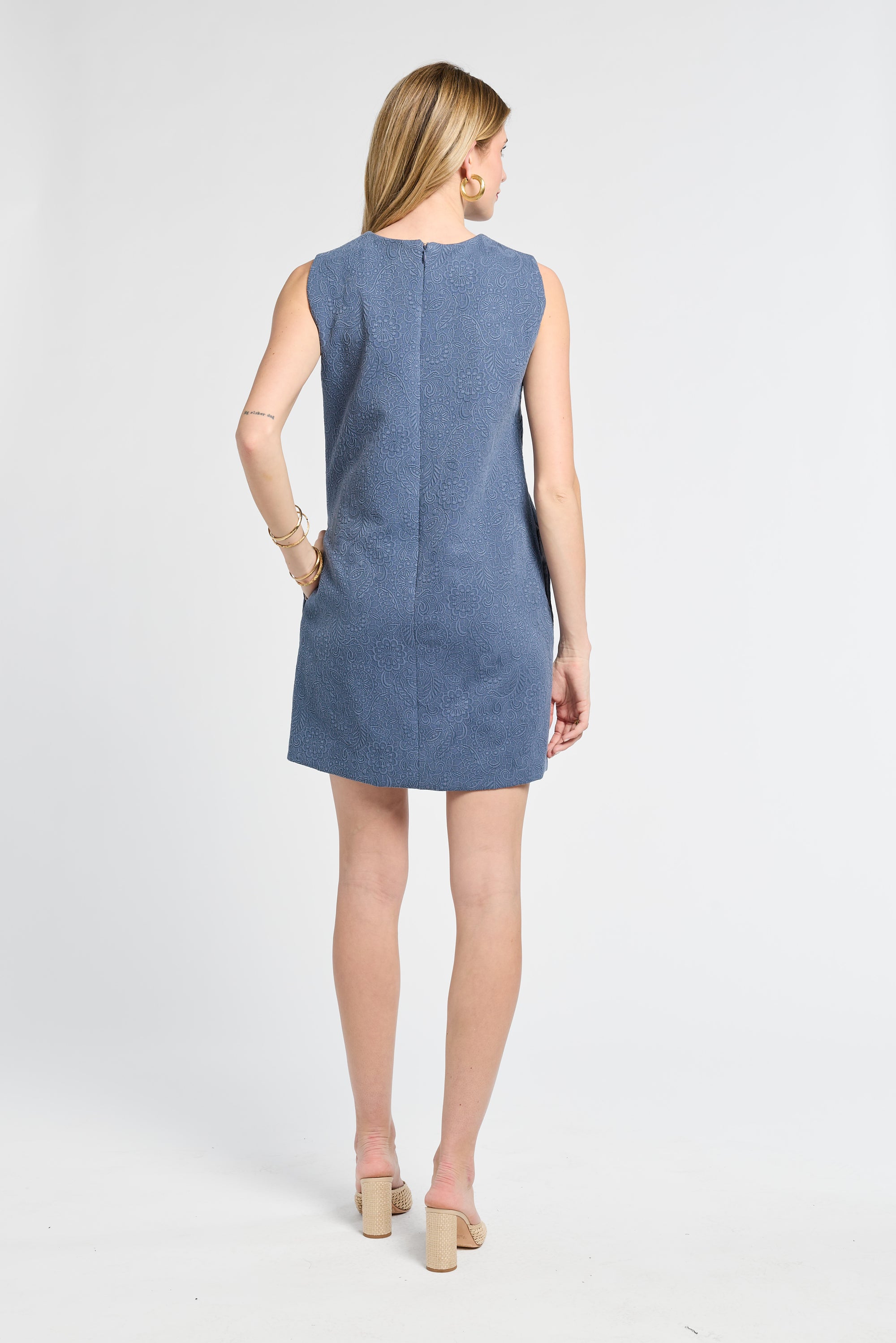 Woman wearing a blue floral sleeveless dress on a white background