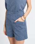 Person wearing a blue floral sleeveless top and shorts on a white background