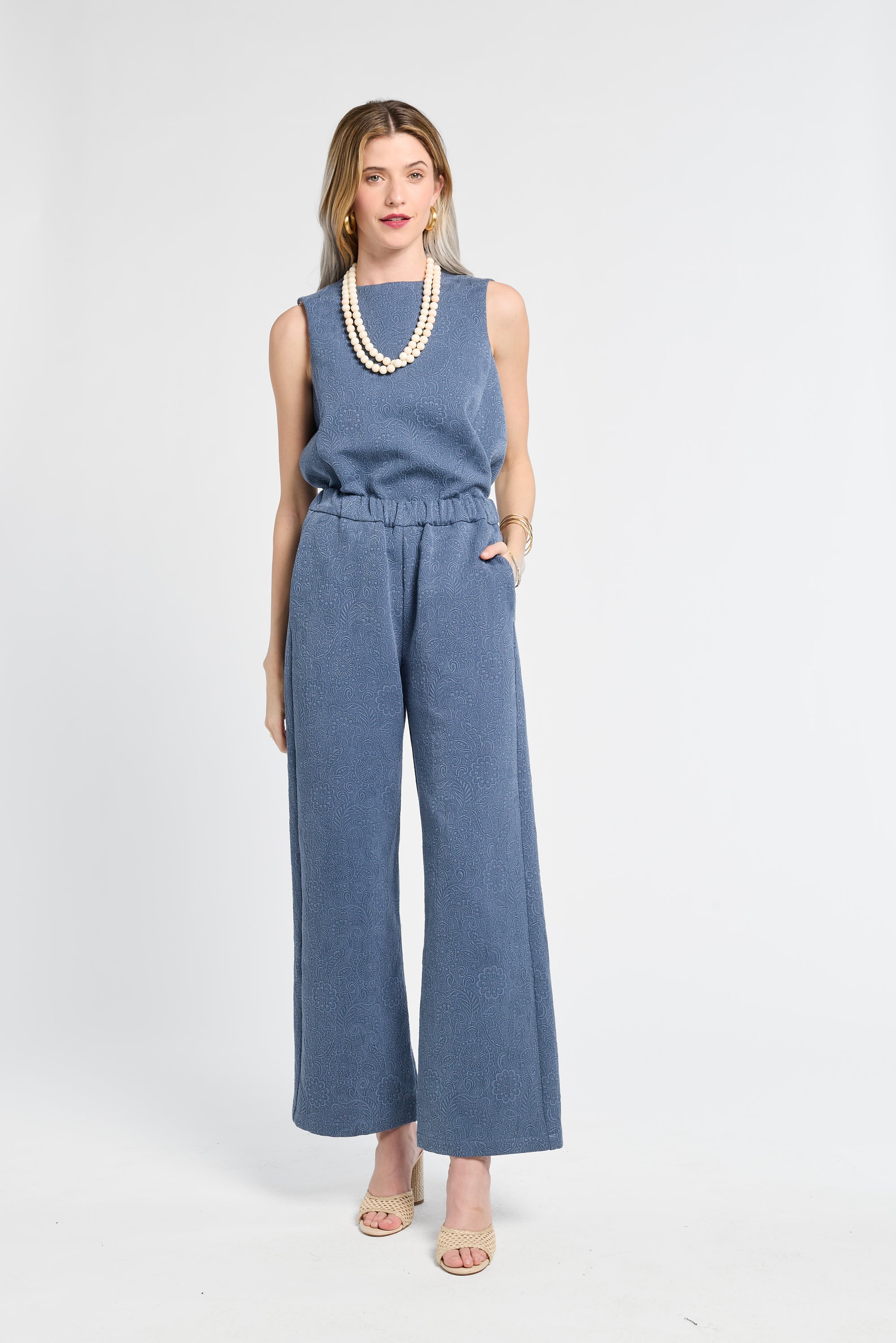 Woman wearing a blue blouse and pants on a white background