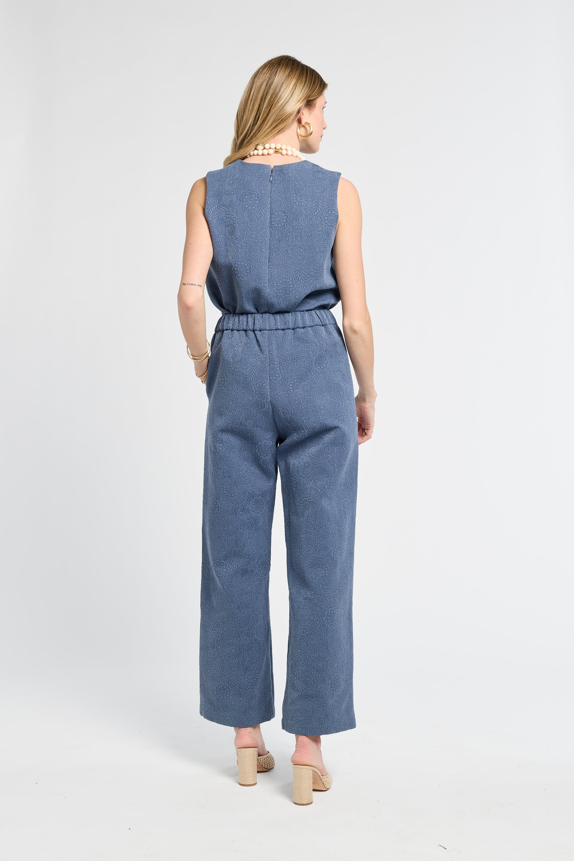 Woman wearing a pair of floral blue pants on a white background