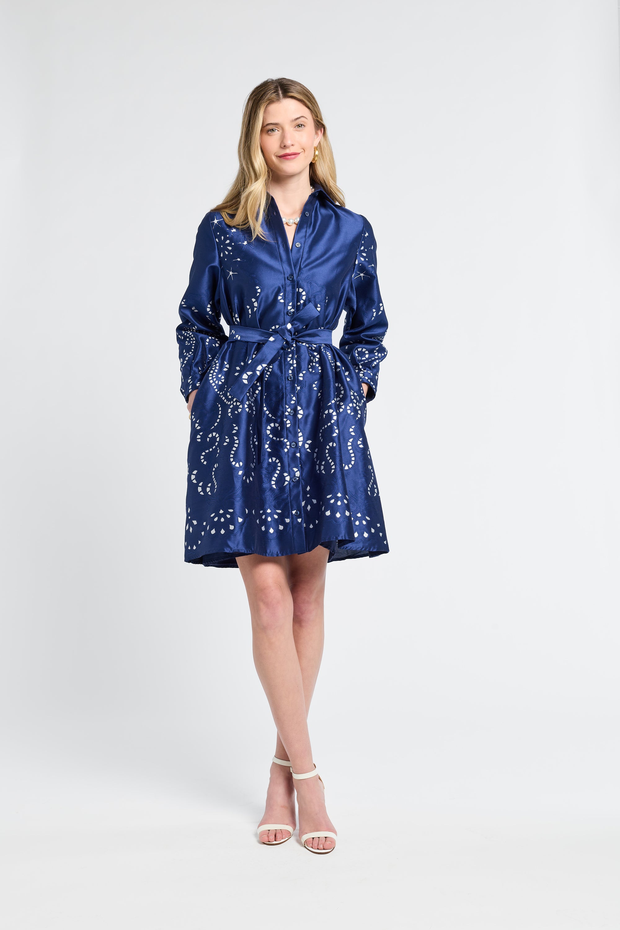 Woman wearing a blue dress with silver swirl patterns on a white background