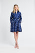 Woman wearing a blue dress with silver swirl patterns on a white background
