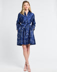 Woman wearing a blue dress with silver swirl patterns on a white background