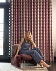 Woman modeling blue denim pants against a pink curtain
