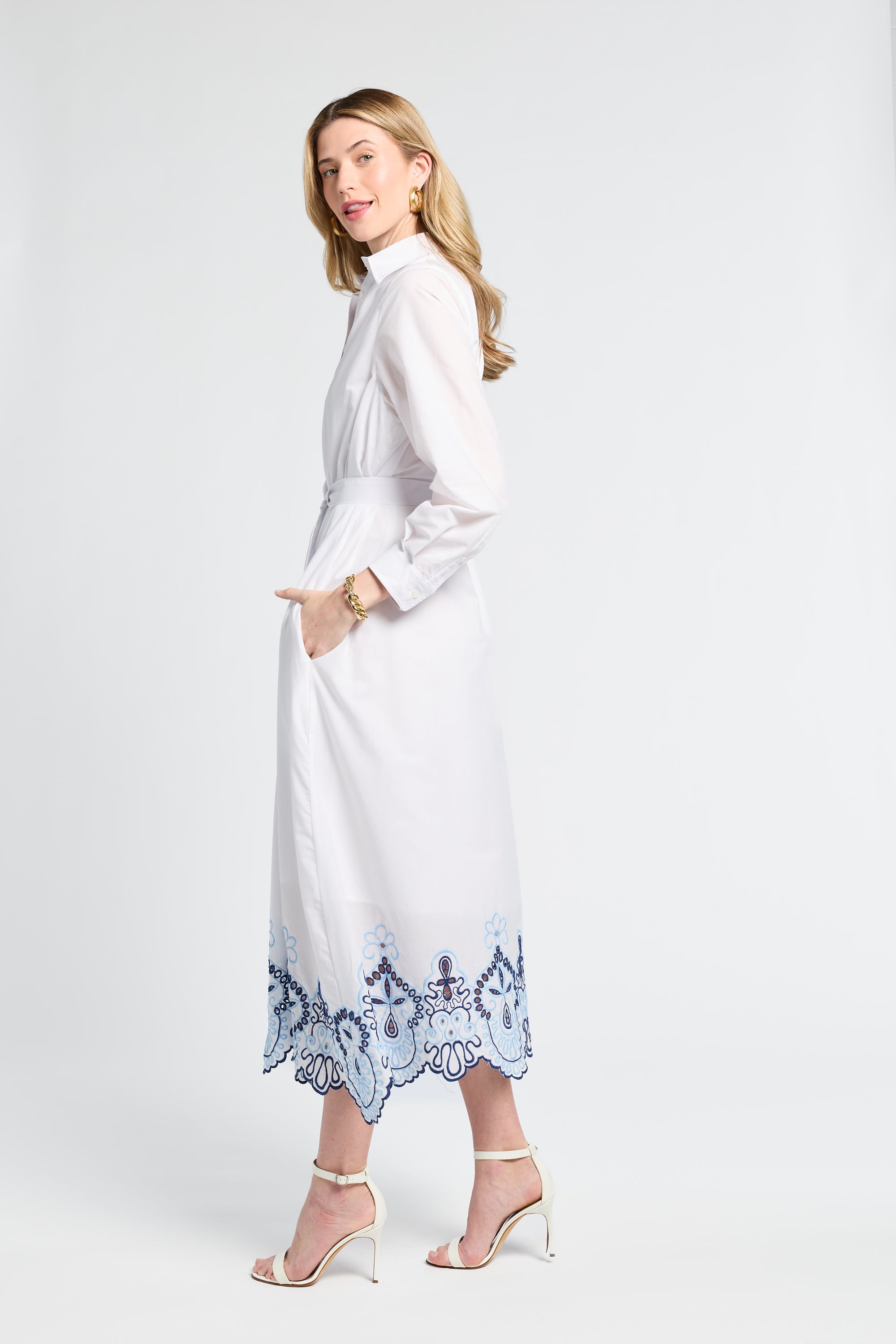 Woman wearing a white dress with blue lace details on a white background
