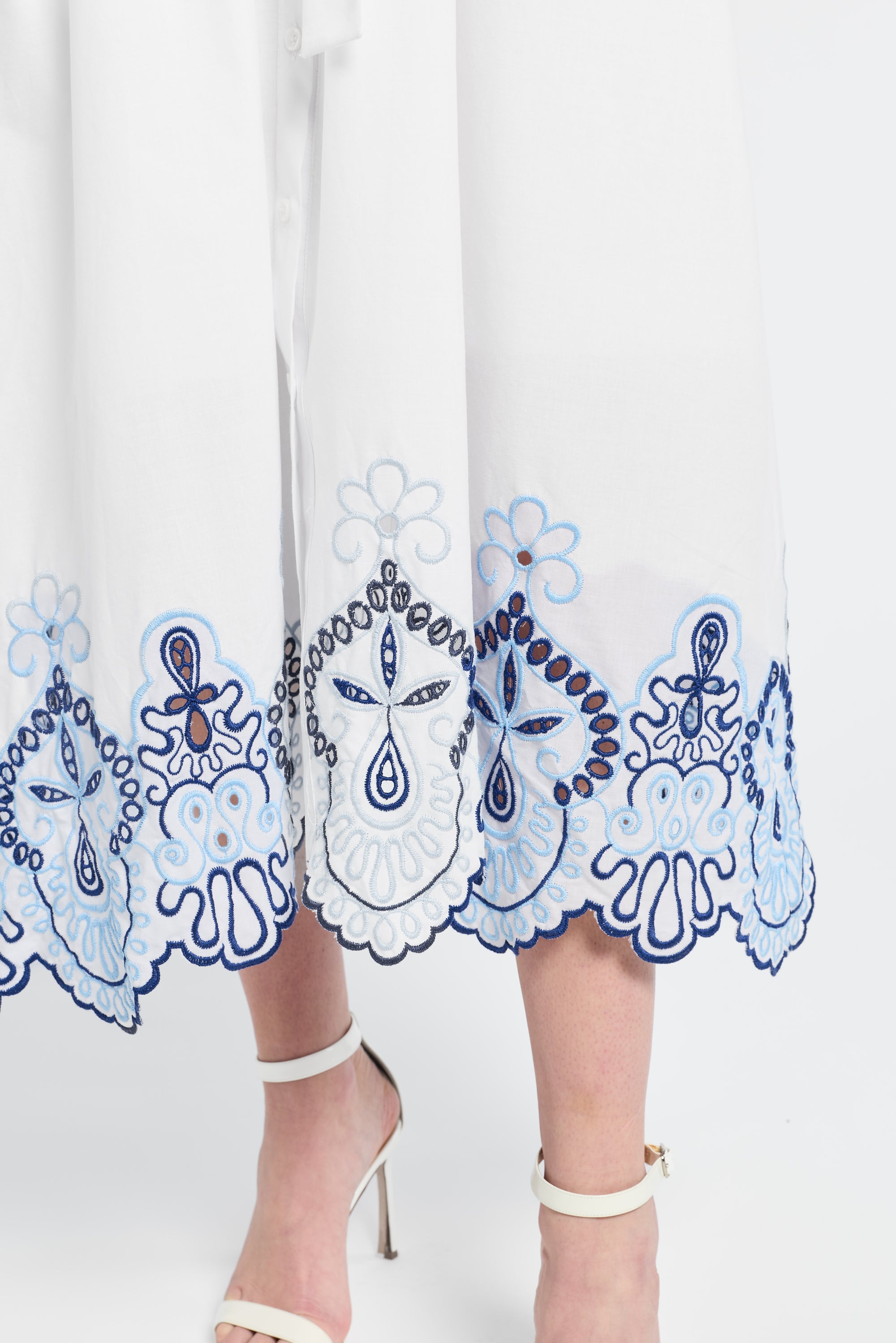 Image of a white dress with blue floral embroidery on the trim on a white background