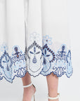 Image of a white dress with blue floral embroidery on the trim on a white background