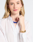 Woman wearing a white blouse with jewelry on a plain background