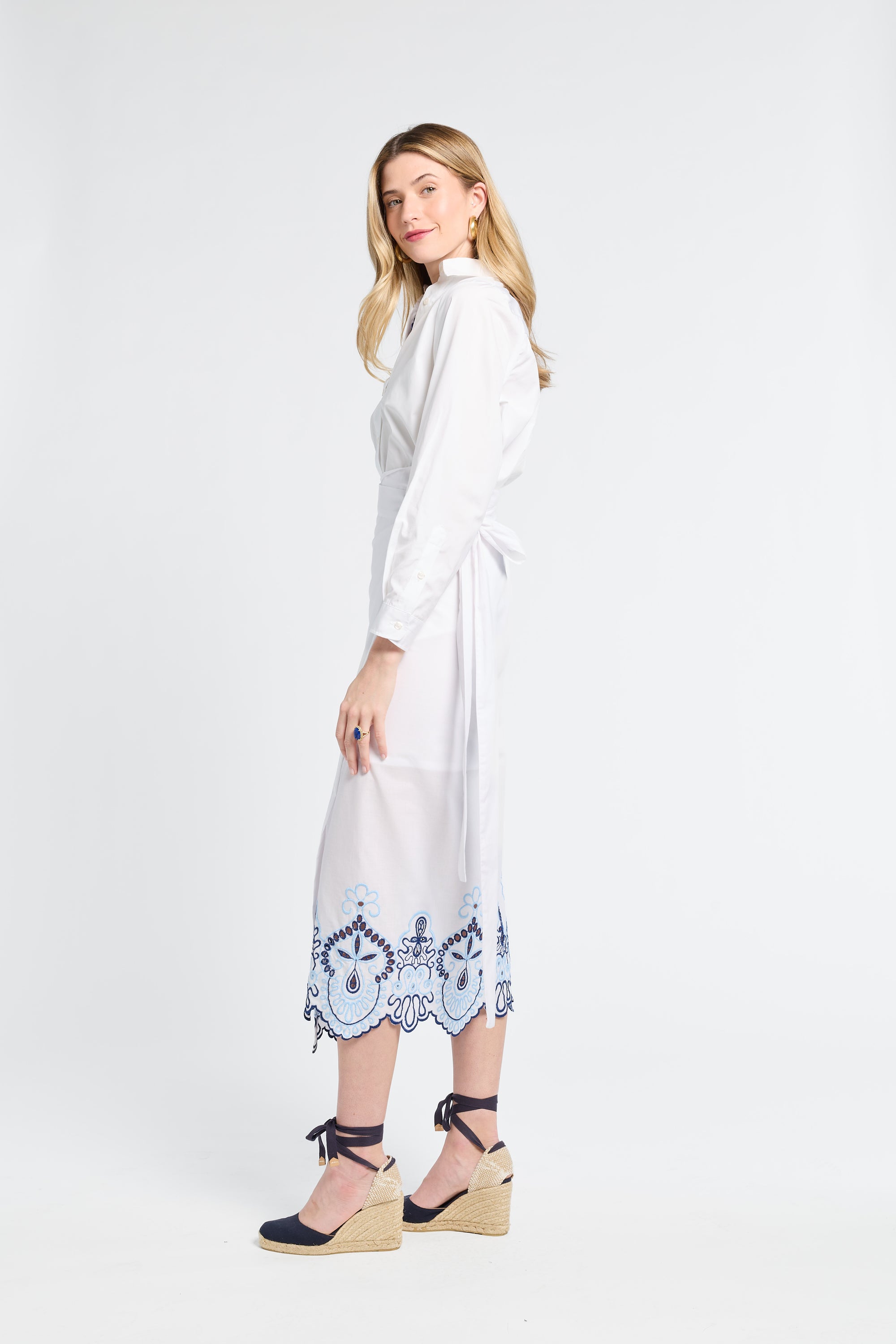 Woman wearing a white wrap skirt with blue patterns on the trim against a white background