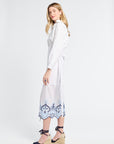 Woman wearing a white wrap skirt with blue patterns on the trim against a white background