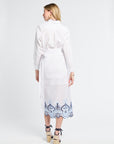 Woman wearing a white blouse and skirt with blue embroidery on a white background